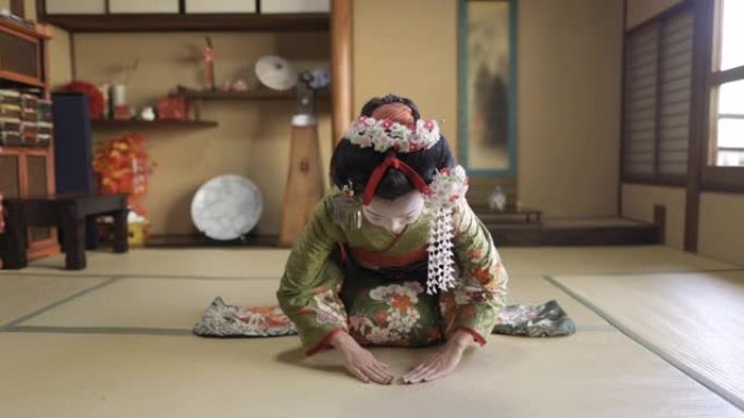舞子 (训练中的艺妓) 坐在高跟鞋上，在日本榻榻米房间鞠躬