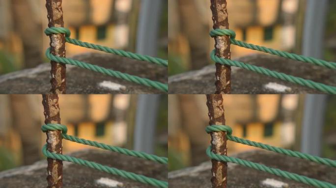 一根绳子在篱笆柱上打结，绳子在与背景隔离的生锈的铁杆上打结。