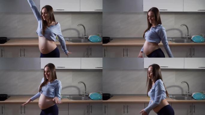 孕妇在厨房跳舞。有趣的手部动作和好心情。复制空间。