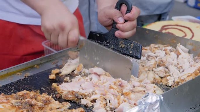 慢动作: 厨师在街头美食节上在烤架上切鸡肉