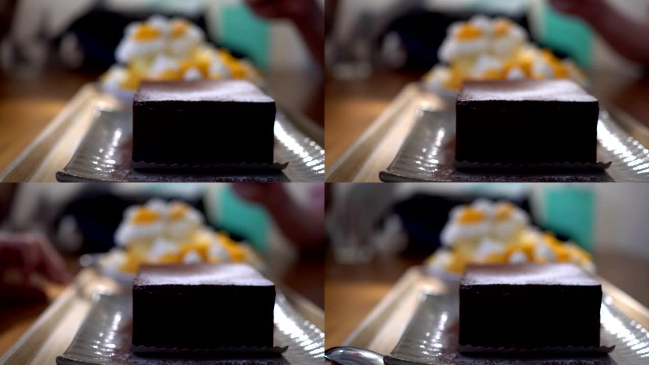 小女孩在餐馆吃甜点。盘子上的巧克力蛋糕和芒果蛋糕的特写。主题在右边。
