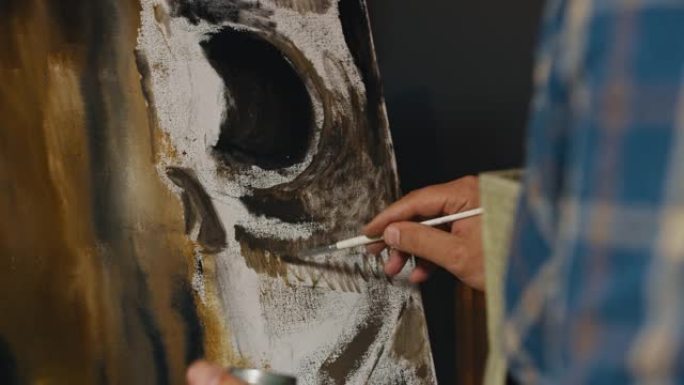 在dark studio中油画过程的特写镜头，艺术家在画布上绘画。