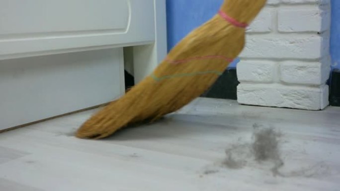 扫帚用白色强化地板扫除房屋中的灰尘。大量污垢和灰尘