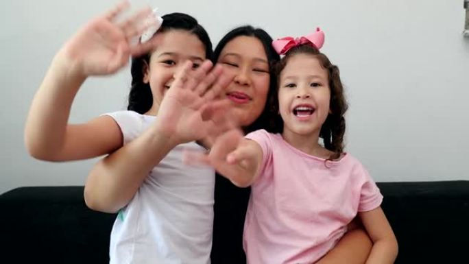 亚洲妈妈向镜头打招呼，抱着多民族的小女孩