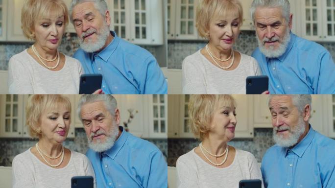 积极的祖母和祖父在智能手机上在线通话视频。微笑的老年人通过视频聊天交谈的肖像。使用智能手机的快乐老家