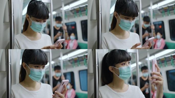 亚洲女性戴着口罩，使用智能手机和耳机，在地铁或火车上通勤时保持社交距离