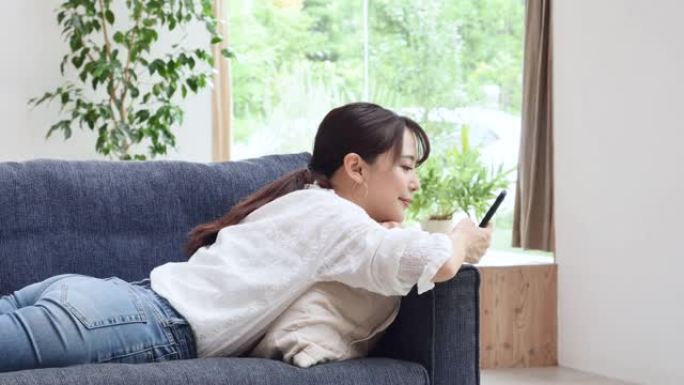 亚洲妇女在沙发上使用智能手机