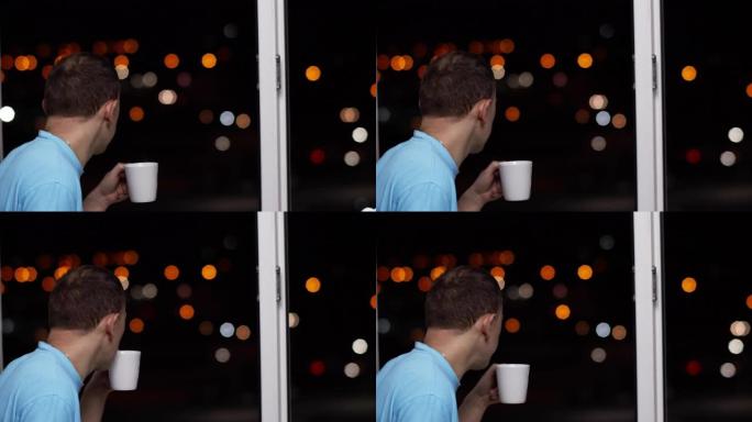 一个男人喝热茶，看着窗外的灯。