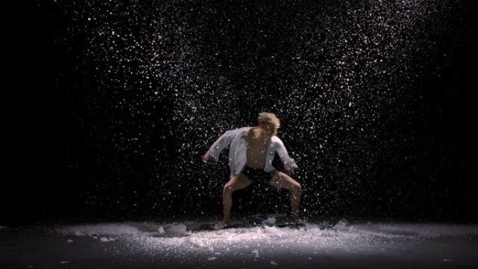 感性的当代芭蕾舞剧以缓慢飘落的雪为背景。这个年轻人在闪闪发光的雪和工作室的灯光中平稳地移动。慢动作