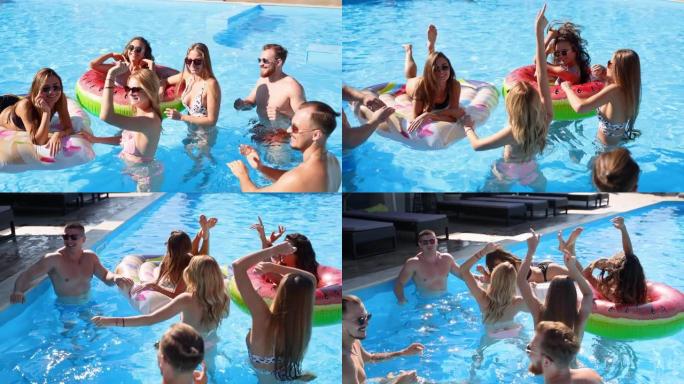 朋友在私人别墅游泳池聚会。在阳光明媚的日子里，穿着泳装的快乐年轻人在豪华度假胜地跳舞，用漂浮物和充气