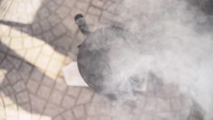 在放入烧烤炉烤肉之前，在狭长的钢锅中燃烧煤的俯视图。烧炭的过程，从烹饪金属锅中冒出灰色烟雾。开放式露