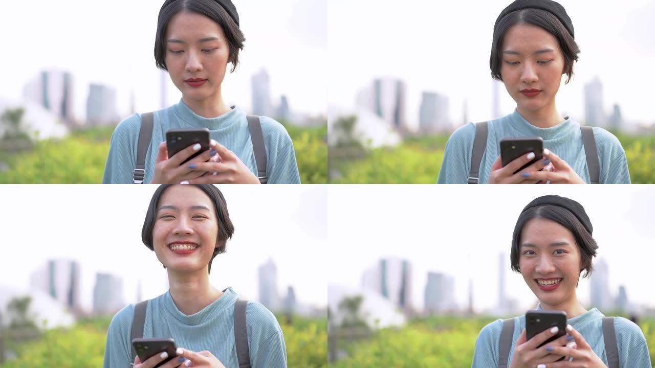 使用智能手机的亚洲女性的特写脸。快乐的白牙女性脸漂亮的脸在户外为特写肖像摆姿势。