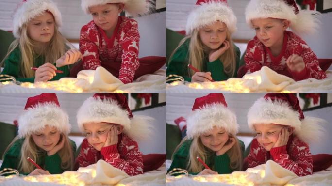 圣诞奇迹愿望清单。戴着圣诞老人帽子的微笑男孩和女孩写信给圣诞老人的礼物。孩子兄弟姐妹躺在家里的床上，