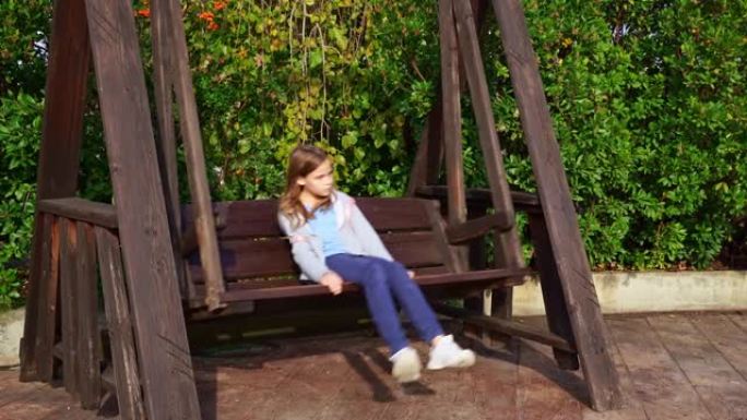 一个十几岁的女孩在一个大的木制秋千上摇摆。