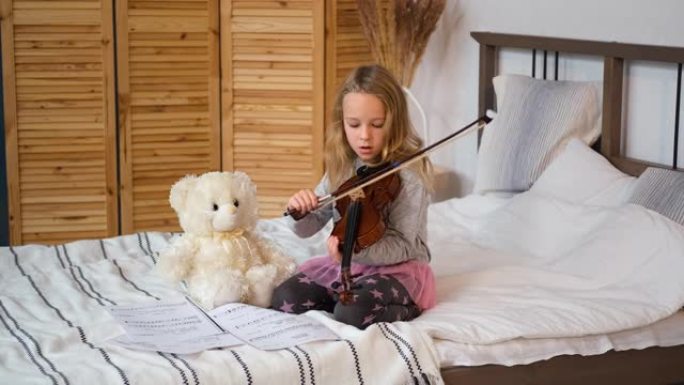 小女孩教玩具熊拉小提琴