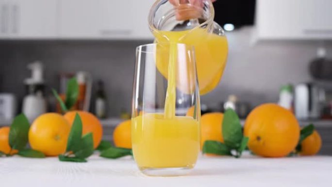 橙汁倒入白色桌子上的玻璃杯中。柑橘汁飞溅慢动作