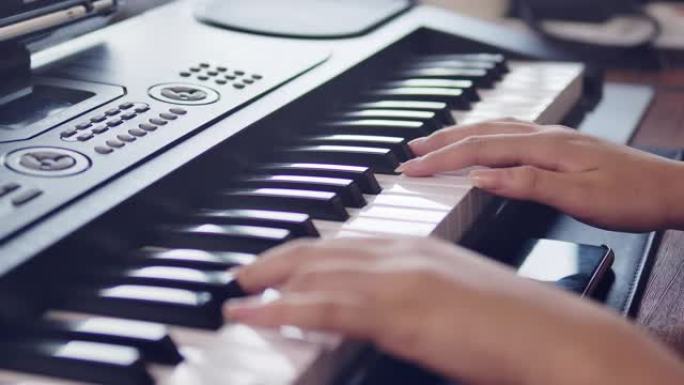 一个年轻的亚洲女孩少年的手拍正在她的房间里练习钢琴键盘音乐。