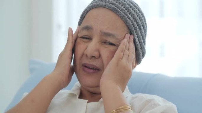 一位戴着头巾的癌症老妇人躺在医院的病床上，她头疼不已。