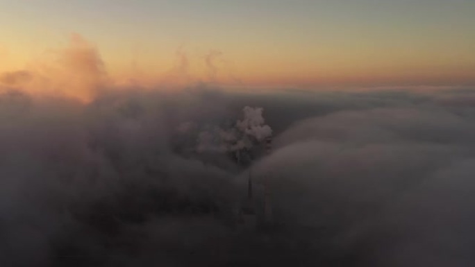 在日落时，空中无人机透过工业管道上的云层