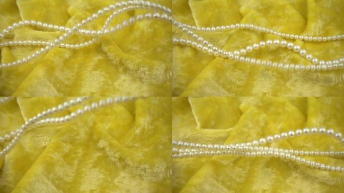 珍珠珠宝在柔软的天鹅绒黄色织物上的飞行和波浪状运动。