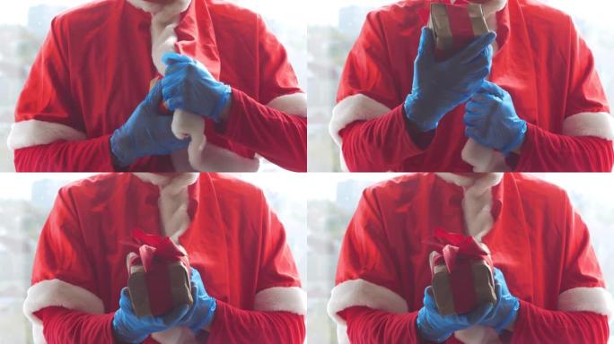 圣诞老人hold提供了一个礼品盒，上面戴着防护手套，手握丝带。圣诞购物，新年安全送货