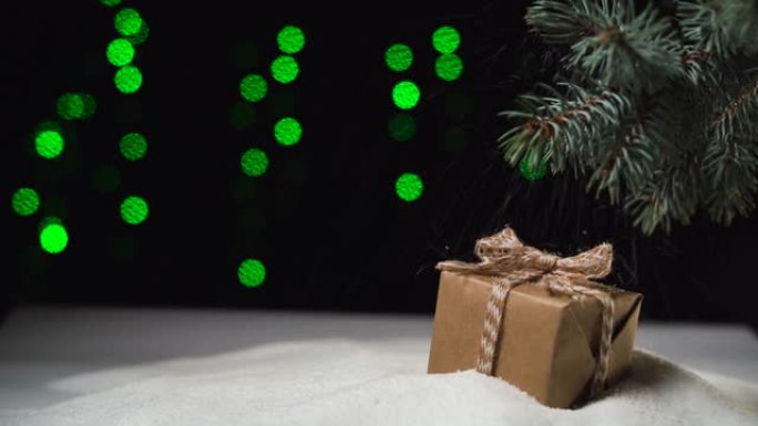 在树下的雪地里躺着一个盒子，里面有一个蝴蝶结，手纸。下雪了。圣诞灯