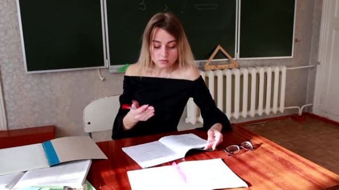 一位严格的年轻金发老师检查学生笔记本中的作业，她对工作结果不满意