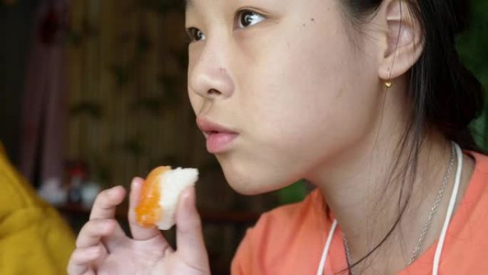 快乐的亚洲女孩在日本餐厅吃泥鱼寿司 (三文鱼和饭团)，有家庭生活方式的概念。