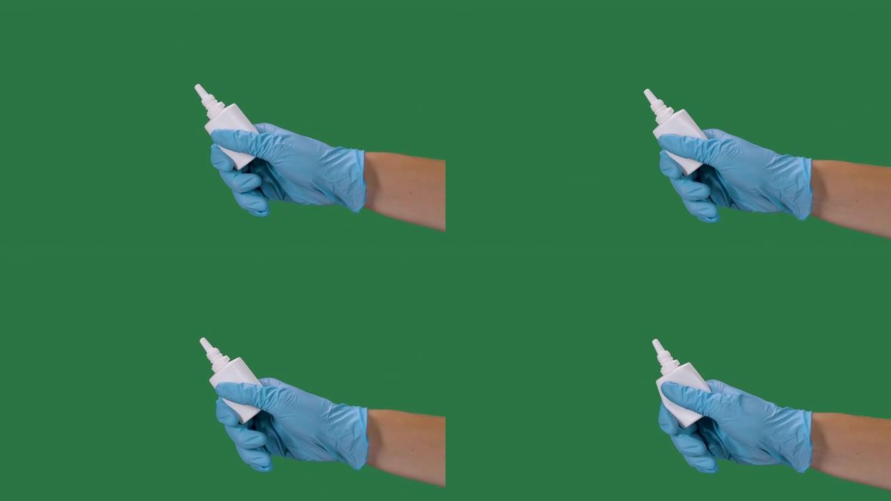 男性双手戴着防护手套，用消毒剂喷雾按压一瓶鼻腔药物。冠状病毒保护。预防大流行Covid 2019。绿
