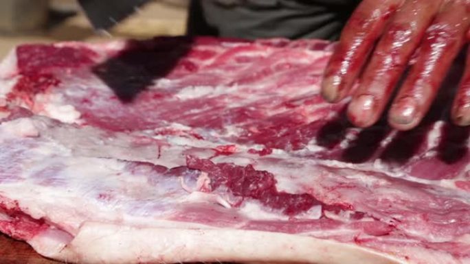 农民用血腥的手切猪肉