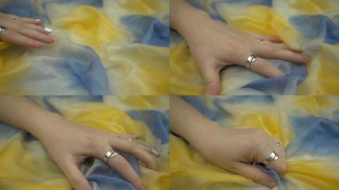 在慢动作中触摸敏感的渐变柔和彩色织物。女人的手轻轻地抚摸着五彩的纺织品。