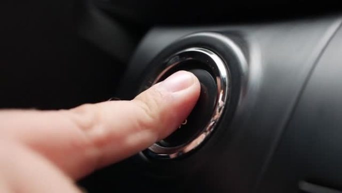 男子正在按下汽车发动机启动按钮。按下按钮启动汽车发动机。特写