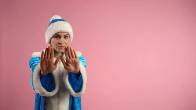 穿着蓝色圣诞服装的害怕女人用手显示停车标志，相机上没有手势。Snow Maiden表现出恐惧的情绪，