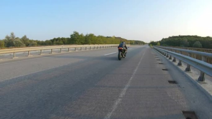 夏季旅途中，男子在高速公路上骑现代运动摩托车的鸟瞰图。摩托车手在乡间小路上骑摩托车。旅途中开车的人。