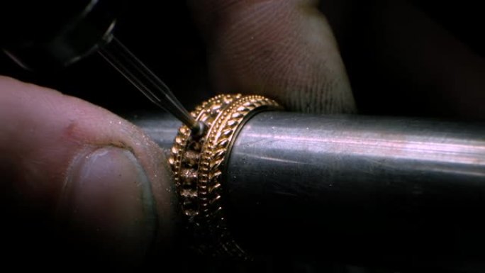 金匠用钻具在金戒指上打洞。珠宝商正在钻孔以设置宝石