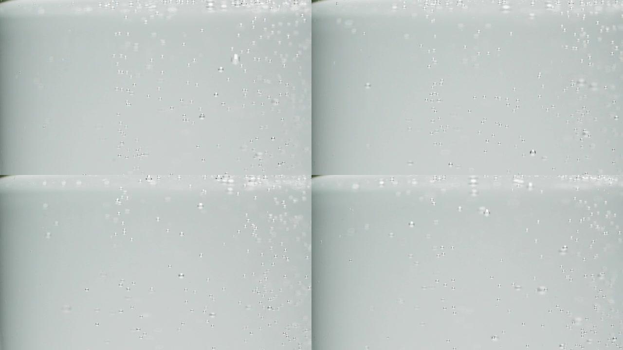 慢动作特写在一杯水，苏打饮料中的白色小气泡