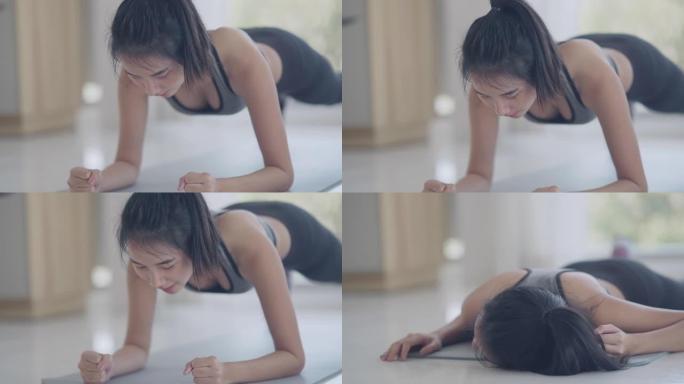 亚洲妇女在卧室里用木板姿势做瑜伽运动，同时从在线课堂教练那里观看