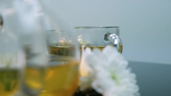 玻璃茶壶里的绿茶花。茶时间仪式。白色背景下的草药茶。茶杯中的鲜花。芳香疗法和阿育吠陀草药