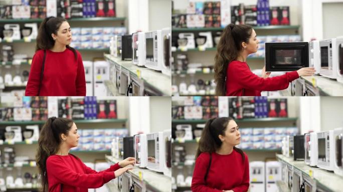 一个年轻漂亮的女人在家电商店选择微波炉。侧视图。消费主义与购物的概念