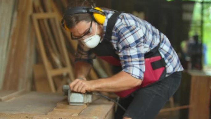 专业木匠佩戴安全个人防护设备，用于保护灰尘和事故。使用电刨加工制造家具制造或车间建筑材料。