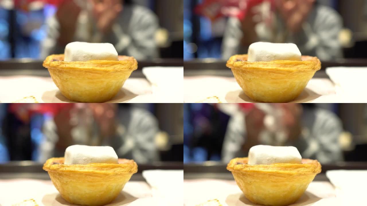 一个孩子在快餐店吃蛋挞。焦点在前面的棉花糖和蛋塔，背景模糊。