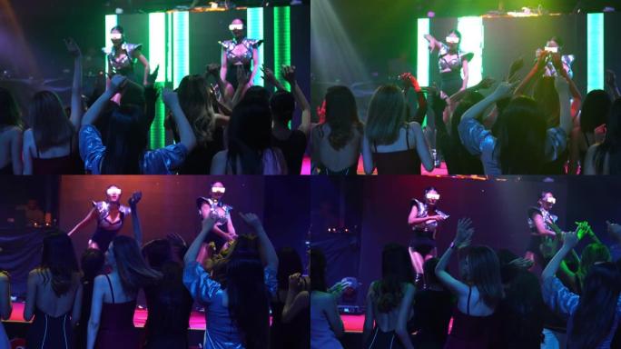 一群人在迪斯科夜总会里随着舞台上DJ的音乐节拍跳舞