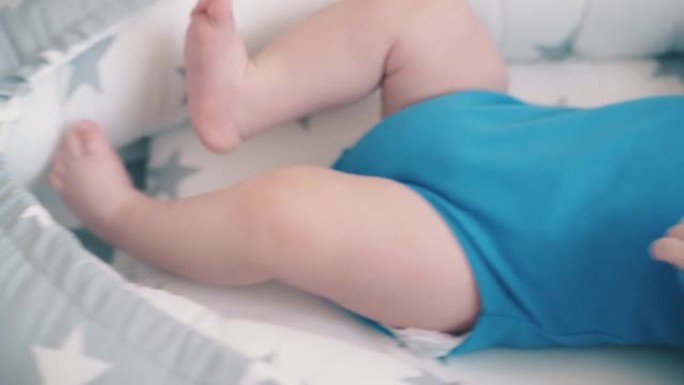 小婴儿踢腿休息在儿童房间的软茧