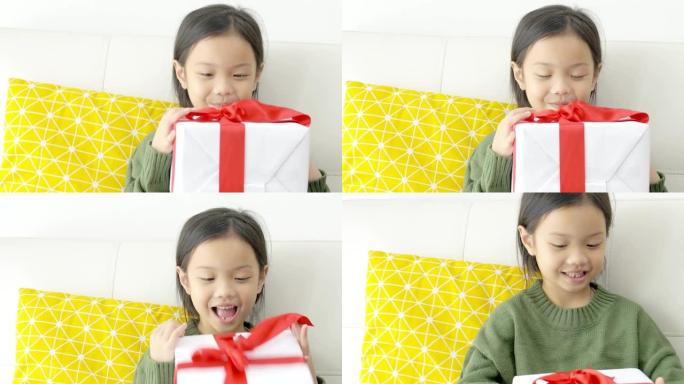 亚洲女孩在家沙发上拿着红丝带礼品盒，节日概念。