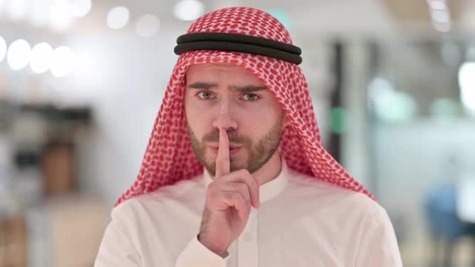 认真的阿拉伯商人将手指放在嘴唇上的肖像