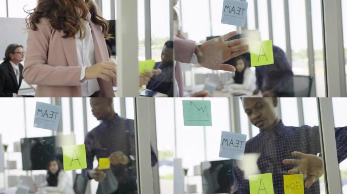 高加索女商人和非裔美国商人在与同事交流想法和解决方案时，在现代办公空间的玻璃内部贴上粘合剂。