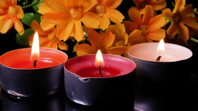 阵亡将士纪念日的蜡烛和黄色花朵。黑暗中燃烧的蜡烛的火焰。沉默一分钟。纪念日。阵亡将士纪念日。悲伤。葬