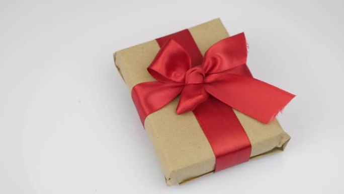带有红丝带系蝴蝶结的包装礼品盒在白色背景下旋转。情人节假期礼物惊喜。情人节或生日用红色蝴蝶结送礼物。