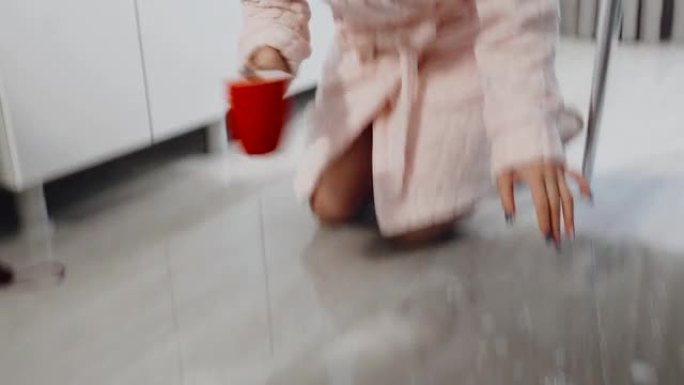 一个女人在家用地板上的杯子擦水。动态场景