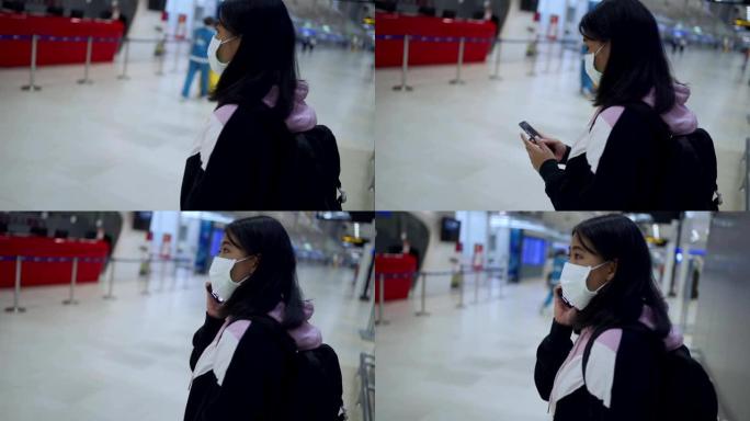 亚洲女性在机场航站楼主厅使用智能手机佩戴医用口罩，旅行导航系统应用，病毒新型冠状病毒肺炎大流行后，新